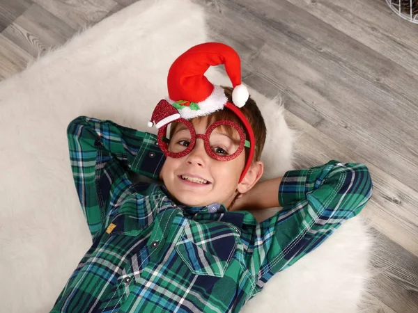 A fiú karácsonyi kalap és szemüveg szóló szőrme szőnyeg — Stock Fotó