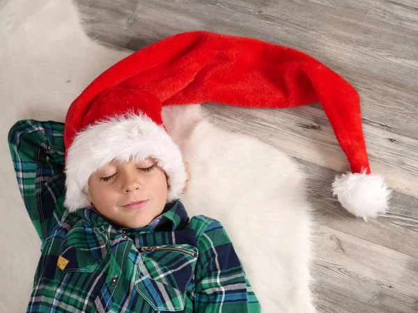 Pojke i jul hatt och glasögon sover på päls matta — Stockfoto