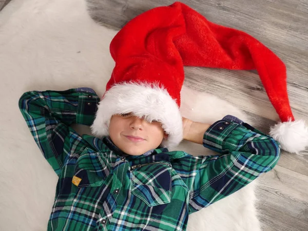 Chłopiec w Boże Narodzenie kapelusz i okulary spanie na dywan z futra — Zdjęcie stockowe