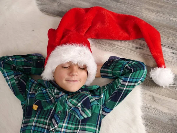 Garçon en chapeau et lunettes de Noël dormant sur un tapis de fourrure — Photo