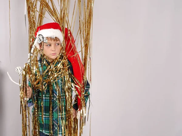 Garçon en chapeau de Noël debout dans la guirlande d'or — Photo