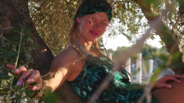 Młody hipis kobieta z okulary siedzi na drzewie — Wideo stockowe
