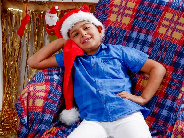 Garçon en chapeau de Père Noël assis sur le fauteuil — Photo