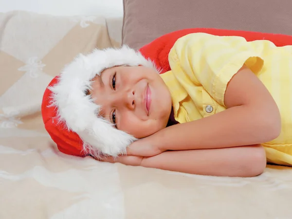 Chlapec v vánoční čepice na pohovce — Stock fotografie