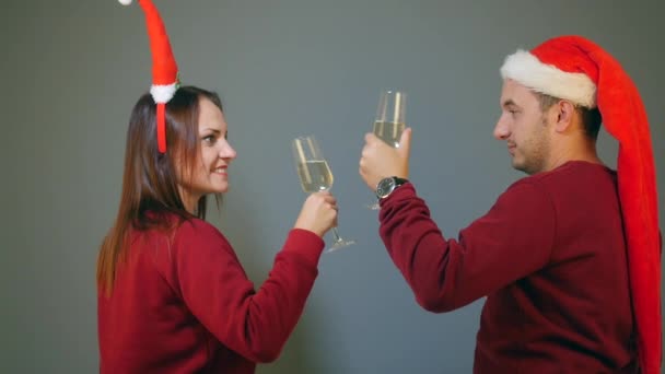 Casal em chapéus santa clinking com taças de champanhe e celebrando o ano novo — Vídeo de Stock