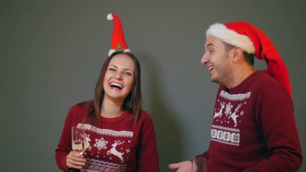 Paar in santa hoeden rammelende met champagneglazen en Nieuwjaar vieren — Stockvideo