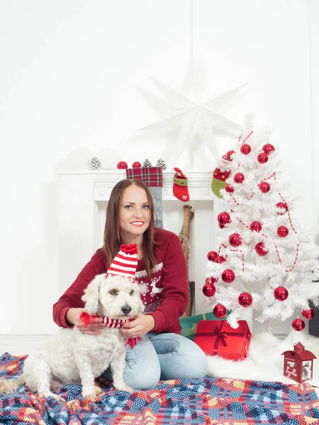 Bela mulher se divertindo com seu cão, tanto em roupas de Natal — Fotografia de Stock