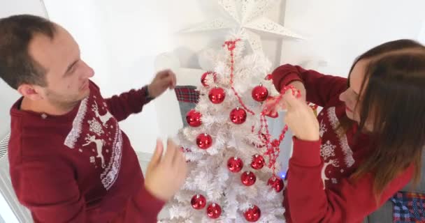 Ευτυχισμένο ζευγάρι στα Χριστούγεννα ρούχα διακόσμησης λευκά χριστουγεννιάτικα δέντρα — Αρχείο Βίντεο
