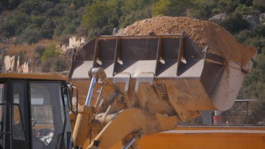 Yol inşaat çalışmaları sırasında taş çakıl ile yüklenen kova closeup.