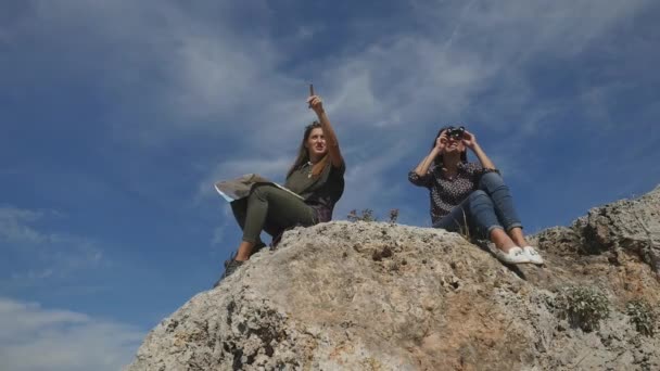 Молоді жінки подорожують з картою, дивлячись далеко через бінокль — стокове відео