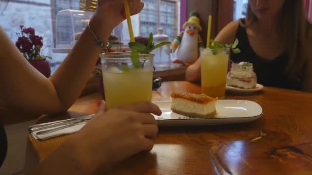 Young women drinking lemonade and eating cakes at the cafe — Stock Video