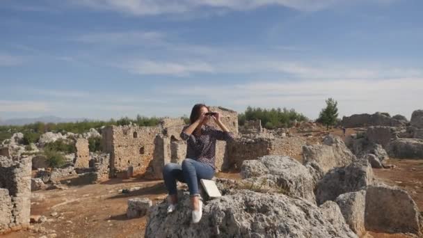 Молода жінка подорожує з картою, дивлячись далеко через бінокль — стокове відео
