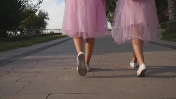 Дві жіночі ноги в тюлевих спідницях і кросівки, що ходять на відкритому повітрі — стокове відео