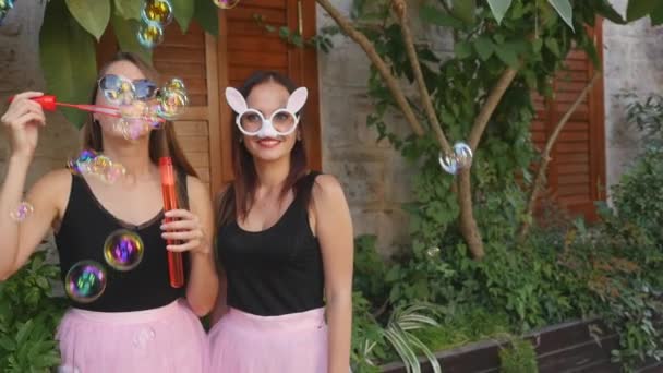 Young funny women blowing party bubbles at the camera — Stock Video