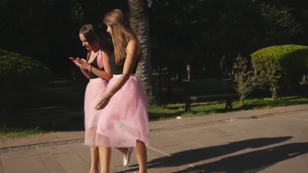 Två vackra unga kvinnor i tyll kjolar och sneakers promenader utomhus — Stockvideo