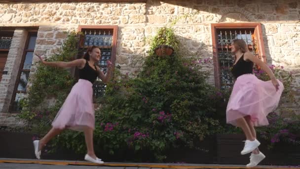 Модный образ жизни две молодые женщины в юбках из тюля смешно встречают друг друга — стоковое видео