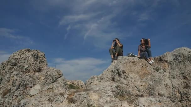 Молодые женщины-путешественницы с картой, смотрящие далеко через бинокль — стоковое видео