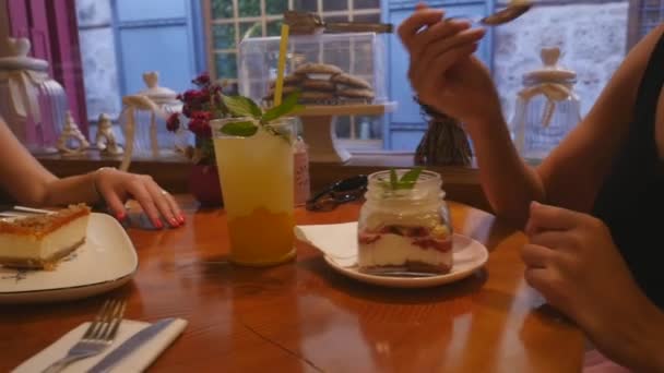 Young women drinking lemonade and eating cakes at the cafe — Stock Video