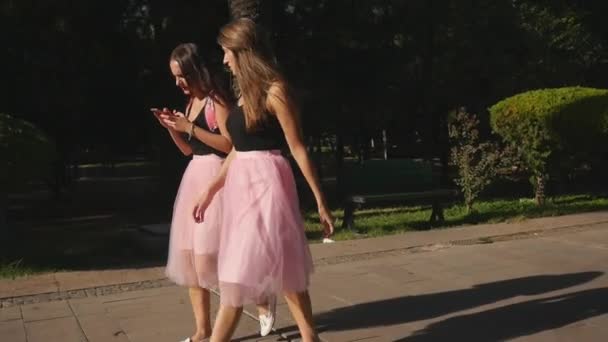 Dos mujeres jóvenes atractivas en faldas de tul y zapatillas de deporte caminando al aire libre — Vídeos de Stock