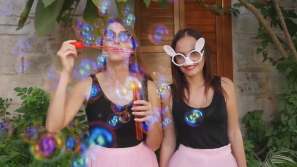Young funny women blowing party bubbles at the camera — Stock Video