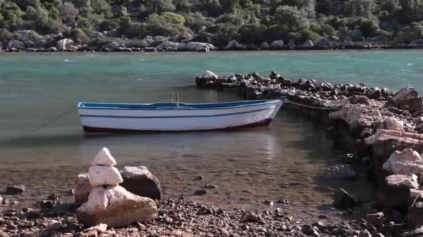 A wooden row boat tied up to a natural stone pier — Stock Video