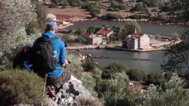 Jeune homme tirant sur les maisons de caméra sur le rivage de la mer — Video