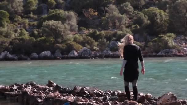 Молодая женщина ходит осторожно по пирсу из натурального камня — стоковое видео