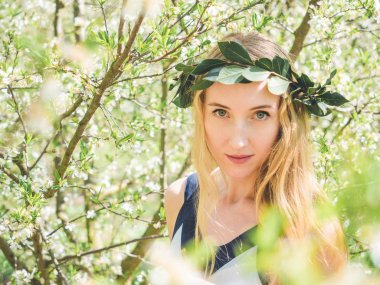 Young beautiful smiling woman in spring blossom trees.