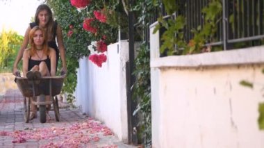 Çiçeklerle el arabasıyla eğlenen kızlar