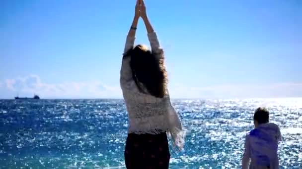 Νεαρή γυναίκα που κάνει γιόγκα κοντά στη θάλασσα με θυελλώδη καιρό — Αρχείο Βίντεο