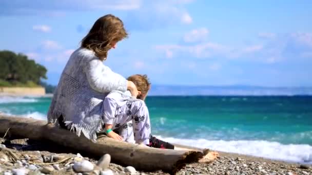 Жінка з маленьким сином, що сидить біля моря — стокове відео