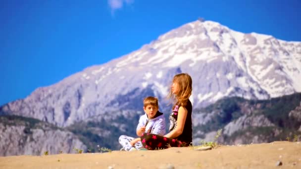 年轻女子和她的儿子平平安安地盘腿坐在沙滩上 — 图库视频影像