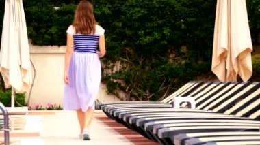 Young woman walking by the simming pool
