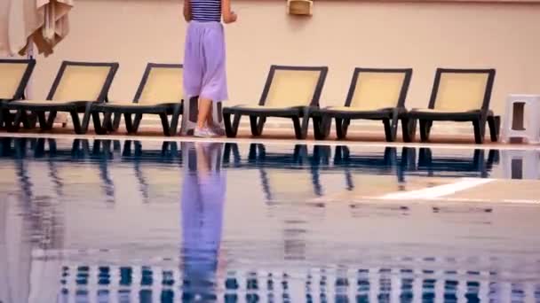 Junge Frau spaziert am Schwimmbad vorbei — Stockvideo