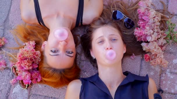 Two smiling cute girls chewing bubble gum — Stock Video