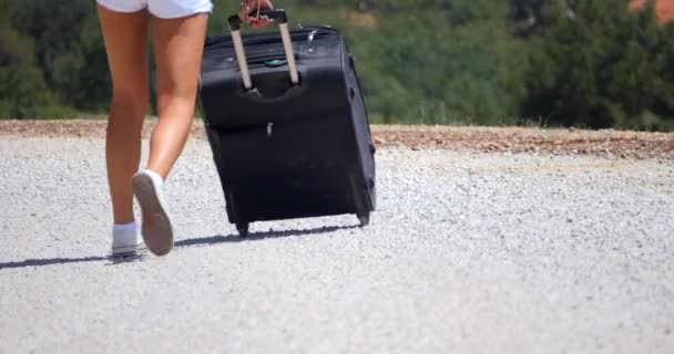 Une femme porte une valise sur la route de cailloux — Video