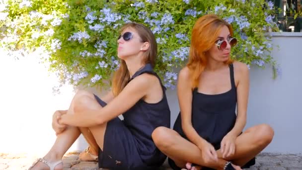 Две улыбающиеся милые девушки жуют жвачку — стоковое видео