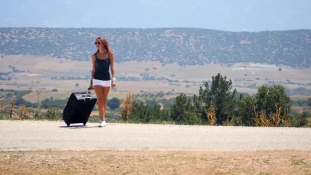 Wanita muda bercelana pendek putih berjalan sendirian di sepanjang jalan dengan koper — Stok Video