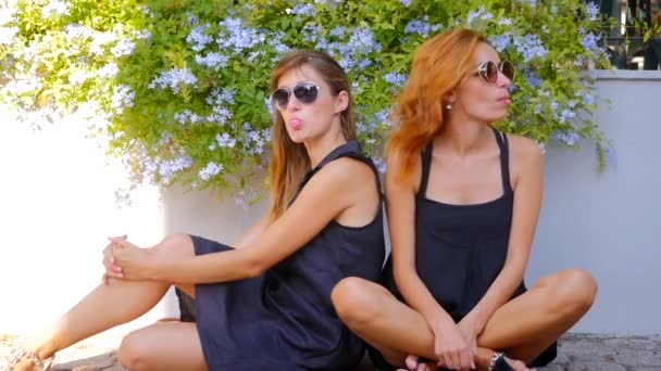 Дві усміхнені милі дівчата жують жувальну гумку — стокове відео