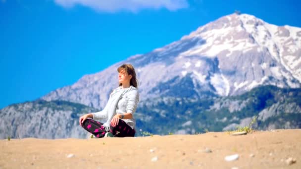 Молодая женщина сидит спокойно скрестив ноги на песке — стоковое видео