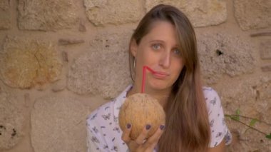 Young smiling woman drinking coconut water