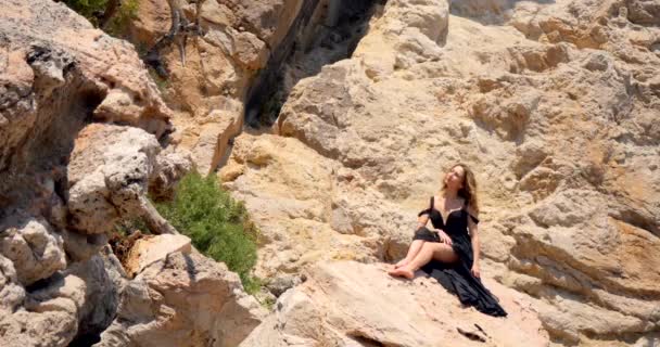 Gyönyörű nő elegáns fekete ruhában a sziklán — Stock videók