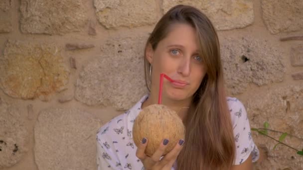 Jovem sorrindo mulher bebendo água de coco — Vídeo de Stock