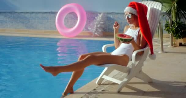 Молодая женщина в шляпе Санта рядом с бассейном — стоковое видео