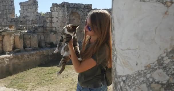 Mujer joven encontró un gato sin hogar en la ciudad antigua Perge, museo histórico antiguo al aire libre — Vídeos de Stock