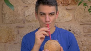 Young cute man drinking coconut water