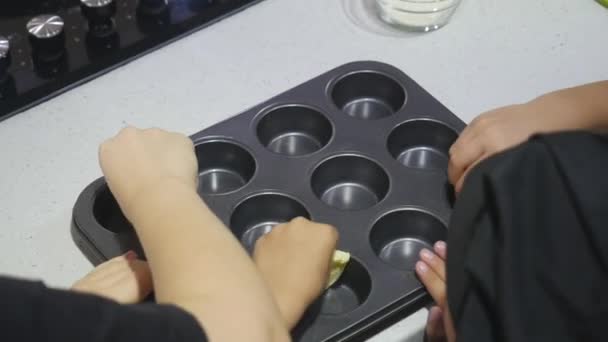 Les mains d'enfants remplissent des moules de muffins avec du beurre — Video