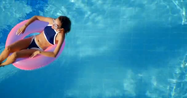 Woman relaxing in a pool on the pink inflatable ring — Stok video