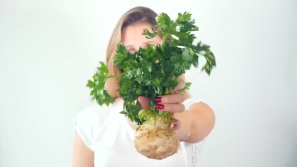 Defocused young woman showing fresh celery root — Stock Video