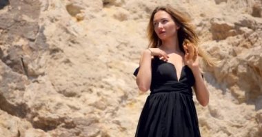 Kayalar üzerinde derin cutout zarif siyah elbise ile güzel kadın